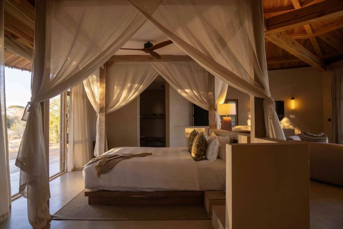 A bedroom with a canopy bed, a bedside table, and a nightstand.