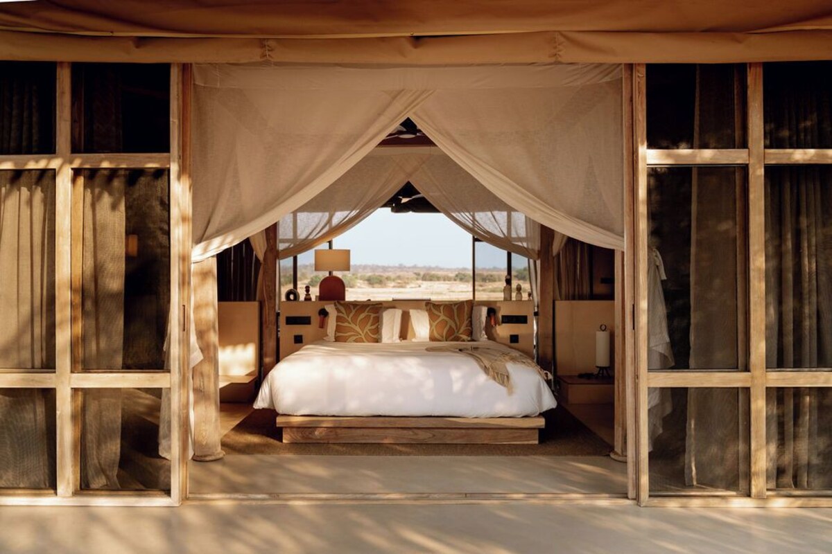 Una cama con dosel, paredes de madera y vistas al desierto.