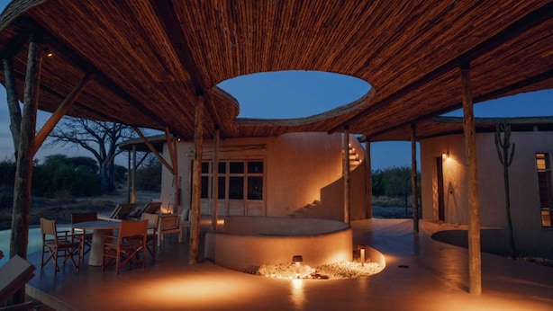 Un espace de restauration en plein air doté d’un aménagement de sièges incurvé, d’un foyer central et d’une structure de plafond en bois remarquable.