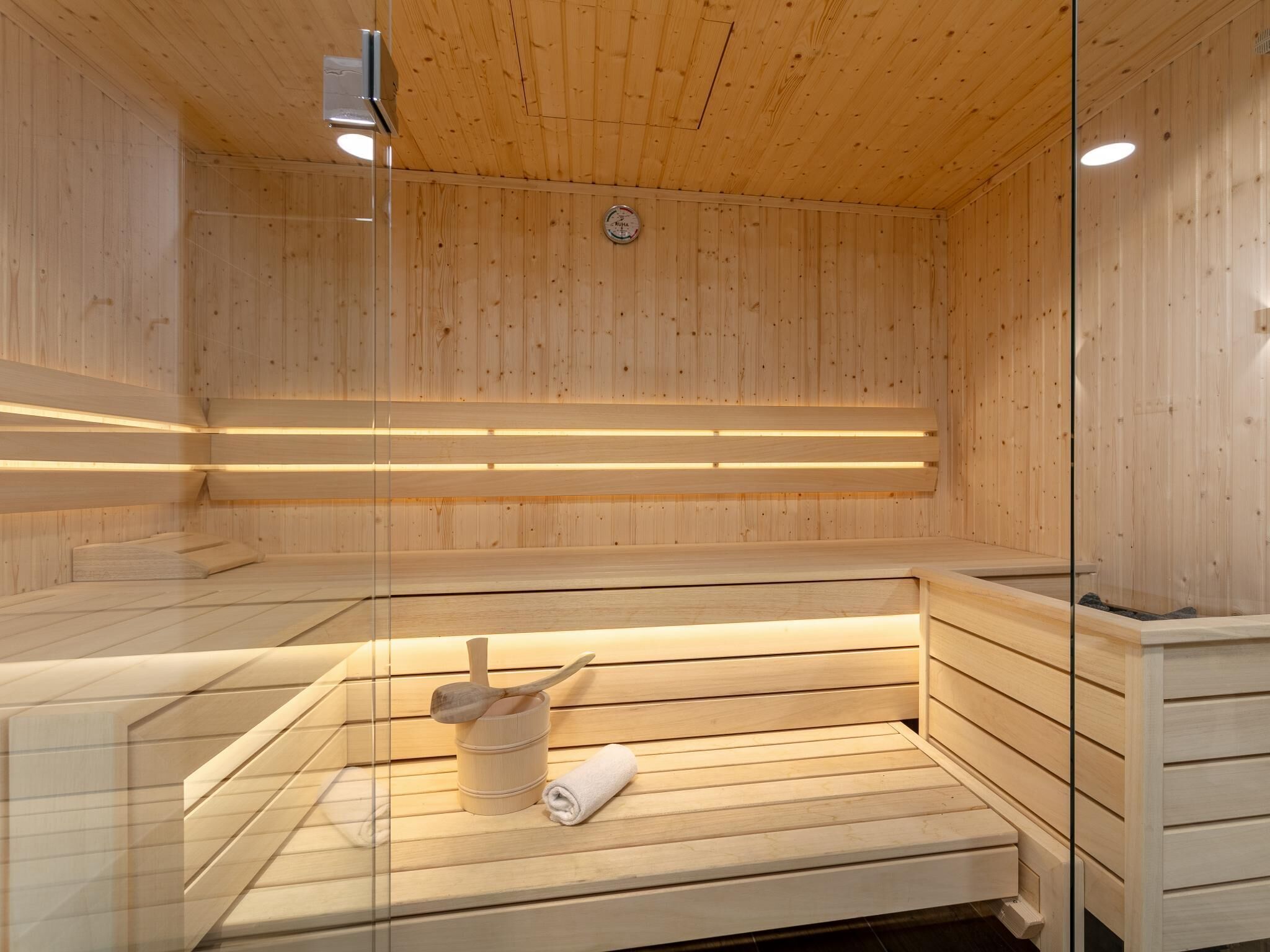 Een houten sauna met banken en een houten emmer met een handdoek.