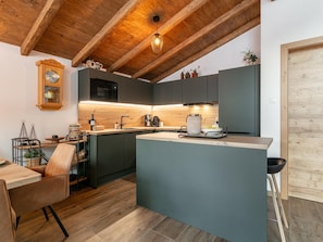 Eine moderne Küche mit Holzboden, einer zentralen Kochinsel und einem Essbereich mit Holztisch und Stühlen.