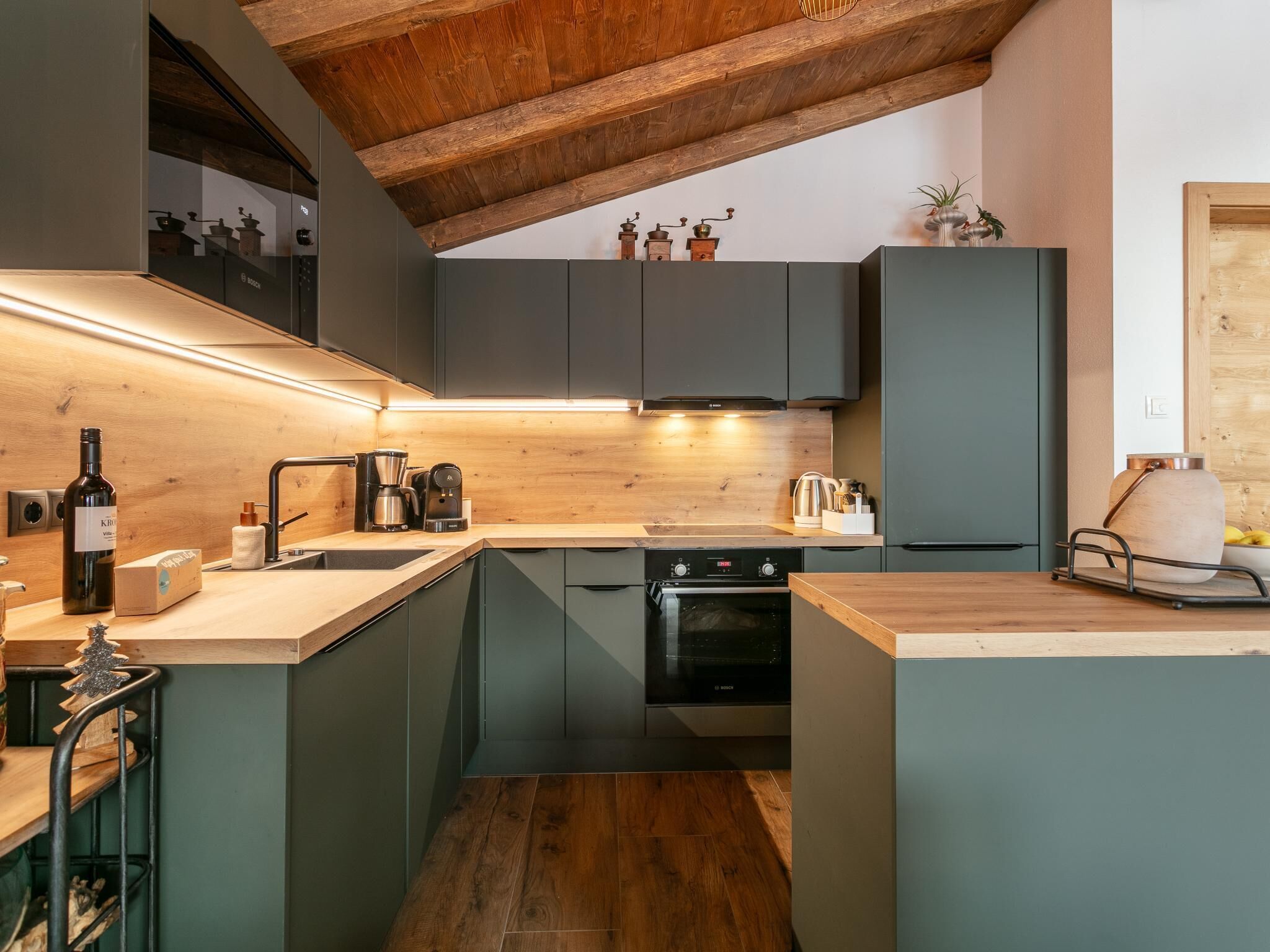 Una cocina compacta con armarios oscuros, techo de madera y horno empotrado.