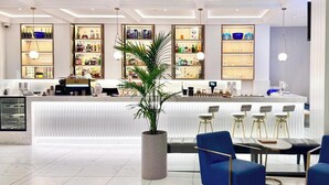 A modern hotel lobby with a reception desk, bar area, seating, and a large potted plant. - Hilton Surfers Paradise 3 bedroom 2 bathroom ocean and river views (Surfers Paradise)