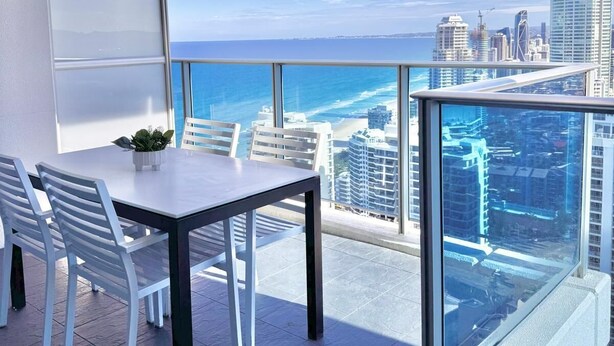 A balcony with a table and chairs, overlooking a cityscape and the ocean. - Hilton Surfers Paradise 3 bedroom 2 bathroom ocean and river views (Surfers Paradise)