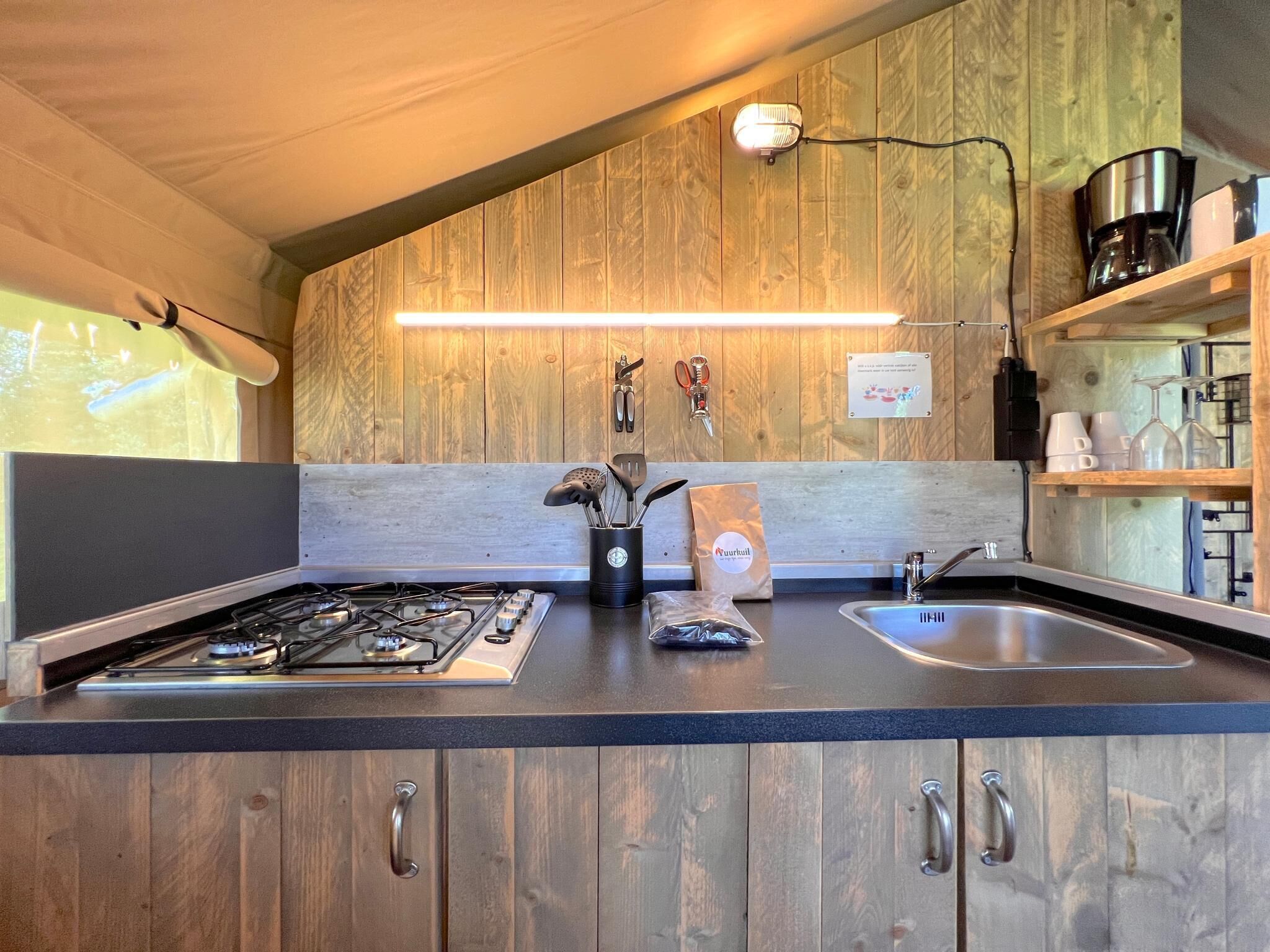 A kitchen with wooden cabinets, a gas stove, a sink, and a coffee maker.