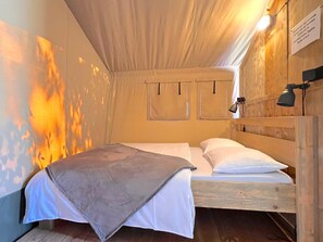 Een gezellige kamer met een bed, een houten hoofdbord en een wandlamp.