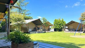 Un'area patio con un tavolo in legno, una pianta in vaso e un'altalena.