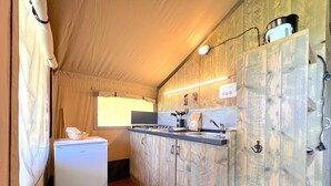 Una cucina compatta con mobili in legno, un piccolo frigorifero e servizi essenziali.