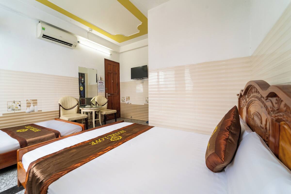 A hotel room with two beds, a desk, a chair, and a TV on the wall.