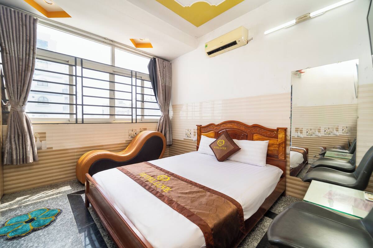 A hotel room with a bed, a wooden headboard, a desk, and a chair.