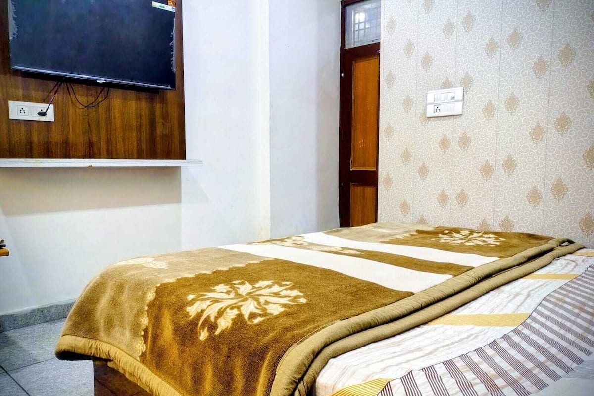 Un dormitorio con cama, televisor montado en la pared, puerta y pared con estampado.