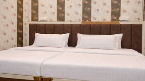 A double bed with a wooden headboard, white bedding, and floral wallpaper.