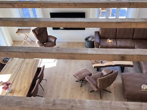 A modern living room with a wooden ceiling, leather sofas, a TV mounted on the wall, and a wooden coffee table. - 5 Star Holiday Home in Skagen (Skagen)