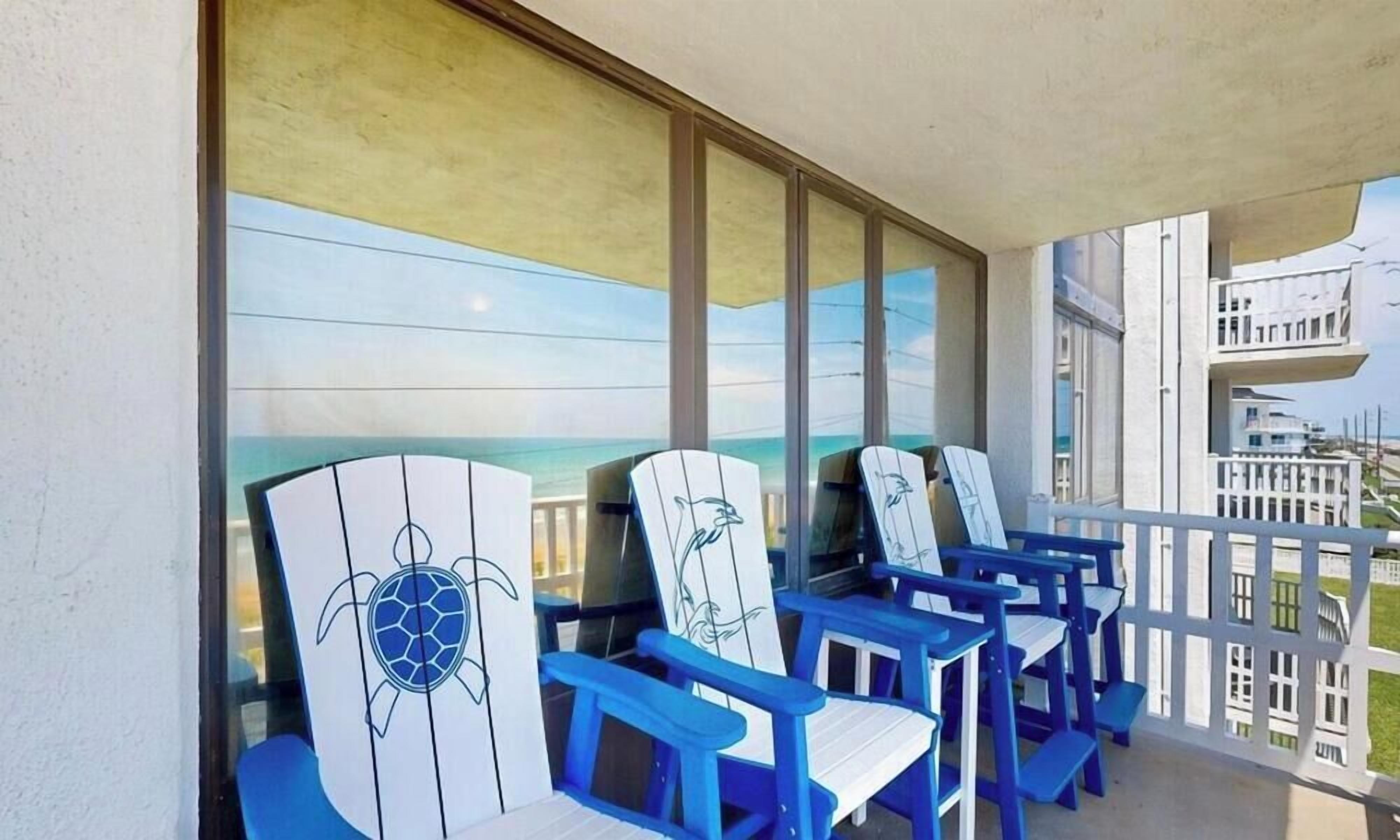 Un balcon avec des chaises bleues et une grande fenêtre donnant sur l’océan.