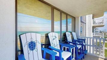 Un balcon avec des chaises bleues et une grande fenêtre donnant sur l’océan.