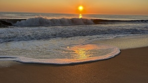 Una spiaggia con onde e un tramonto.