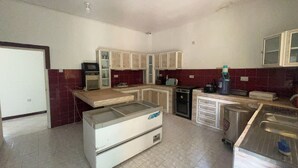 A compact kitchen with basic appliances, a refrigerator, and a sink. - Mango Beach Hotel (Chukwani)