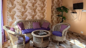 A room with a sofa set, two side tables, and a television mounted on the wall. - K2view Retreat (Darjeeling)