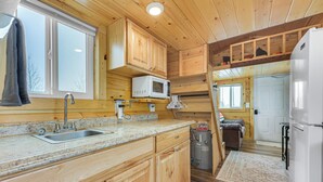 A kitchen with wooden cabinets, a sink, a microwave, and a refrigerator. - Cute Couple's Tiny Home, 8 Mi to Downtown Helena! (East Helena)