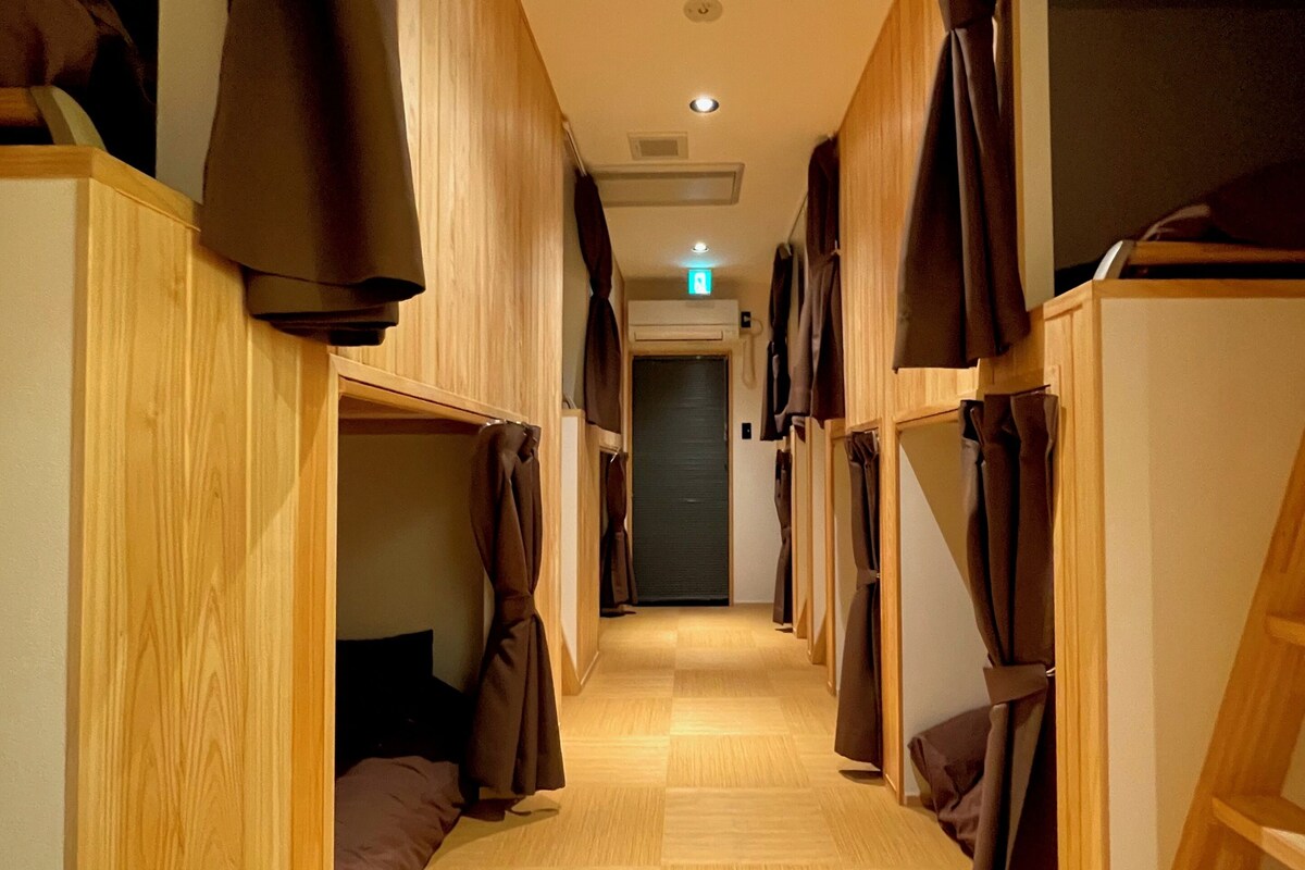 A corridor with bunk beds, wooden flooring, and a ceiling light.