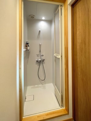 A shower with a handheld showerhead and a wall-mounted faucet, enclosed by a wooden frame. - hatago STAY Shinmachi (Nakatsugawa)
