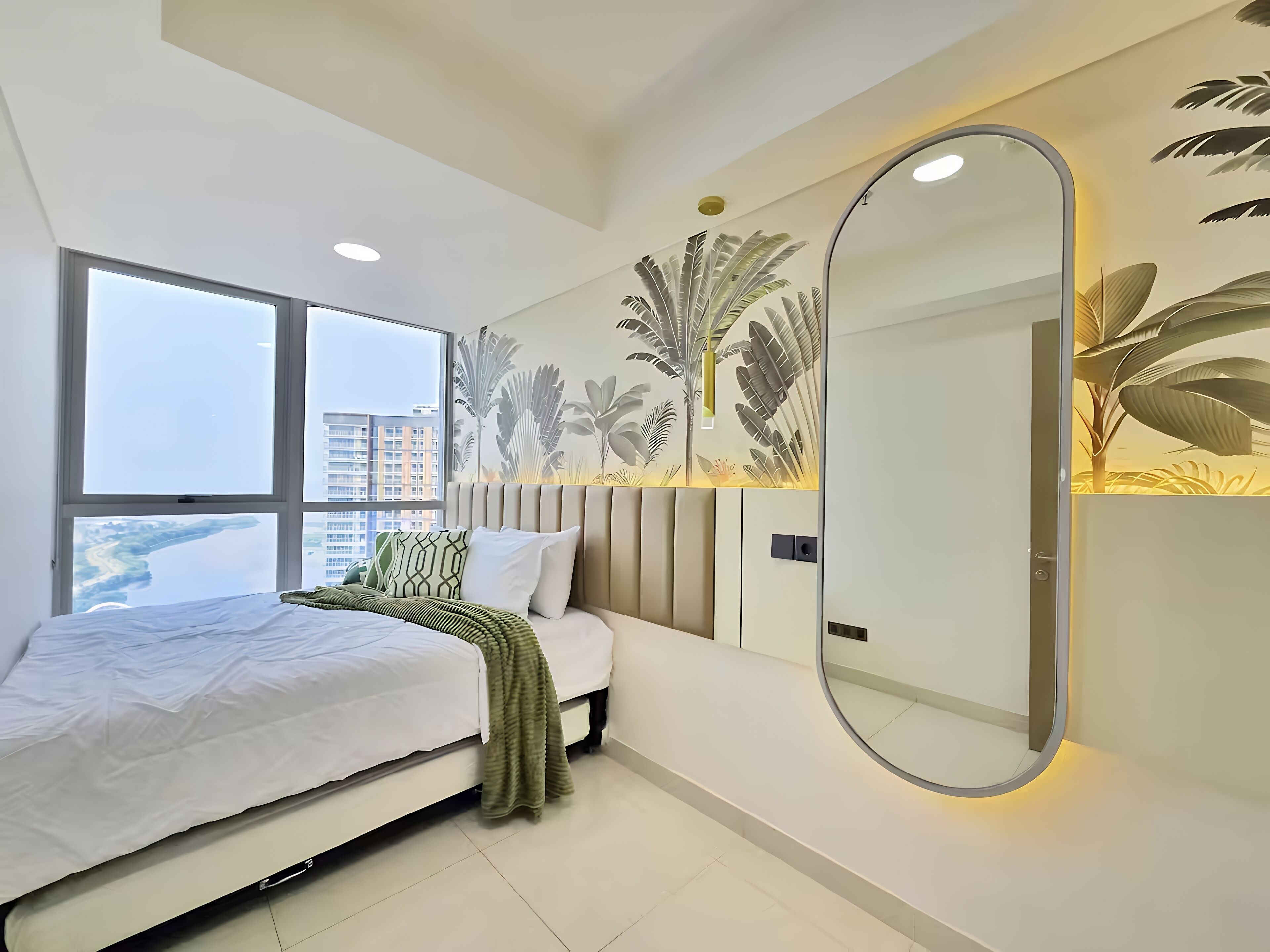 Une chambre moderne avec un grand lit, un miroir rond et une vue sur la ville par la fenêtre.