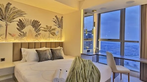 Ein modernes Hotelzimmer mit einem großen Bett, einem Balkon mit Blick auf die Stadt und einer Wand mit Pflanzenkunst.