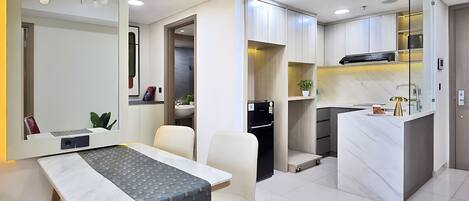 A modern kitchen with a built-in oven, a dining area with a table and chairs, and a hallway leading to a bathroom.