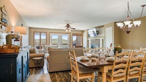 A spacious living area with a dining table set for four, a sofa, and a television mounted on the wall. - Norris Cove Retreat | Spacious Lakeside Living! (LaFollette)