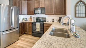 Eine moderne Küche mit Holzschränken, Edelstahlgeräten, Granit-Arbeitsplatten und einer Spüle mit zwei Becken.