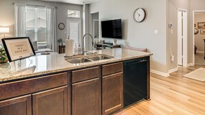Eine moderne Küche mit Granit Arbeitsplatte, Holzschränken, einem Geschirrspüler und einem Deckenventilator.