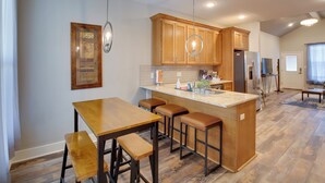 Una cocina con armarios de madera, una isla central con taburetes e iluminación colgante.