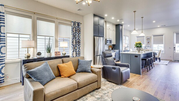 A modern living room with a sofa, a coffee table, and a dining area with chairs. - Designer Wheeler Retreat: Walk to Dining! (Oklahoma City)