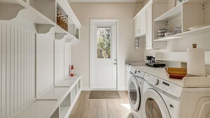 A laundry room with a washing machine, shelves with items, and a door leading to a garden. - Walk to Springs, 700 Ft to Dtwn! Crystal River Gem (Crystal River)