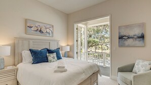 A bedroom with a large bed, a nightstand, a chair, and a view of the outdoors. - Walk to Springs, 700 Ft to Dtwn! Crystal River Gem (Crystal River)