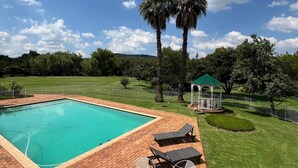 A rectangular swimming pool with a brick deck, surrounded by a well-maintained lawn and a gazebo. - 458 on Manitoba (Pretoria)
