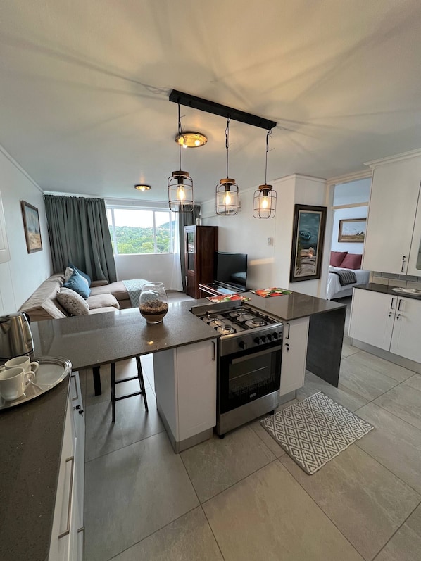 A modern kitchen with a central island, stainless steel appliances, and pendant lighting.