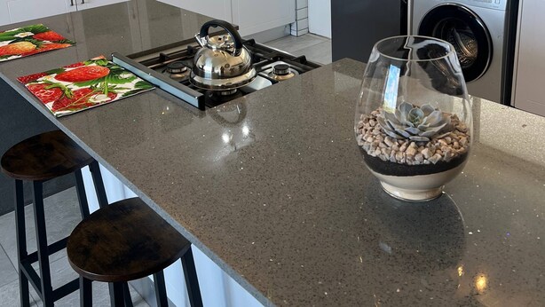 A modern kitchen with white cabinets, a stainless steel refrigerator, a built-in washer and dryer, a granite countertop, and a central island with stools. - 458 on Manitoba (Pretoria)