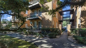 A multi-story residential building with a brick facade, balconies, and a pathway leading to the entrance. - Pet Friendly Midtown Mobile Condo (Mobile)