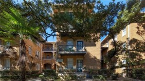 A multi-story building with balconies, a courtyard, and surrounding greenery. - Pet Friendly Midtown Mobile Condo (Mobile)