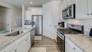 A modern kitchen with white cabinets, stainless steel appliances, and granite countertops. - Shuttle to the Beach! Spacious Home in Millville (Millville)