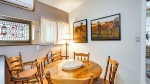 Un'area pranzo con un tavolo e sedie in legno, una finestra con vetri colorati e due quadri appesi al muro.