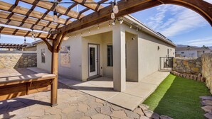 Un patio abrité agrémenté d’une pergola en bois, d’un banc en pierre et d’une pelouse bien entretenue.