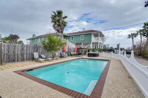 Ein rechteckiger Pool mit einer Holzterrasse und einem weißen Zaun darum.