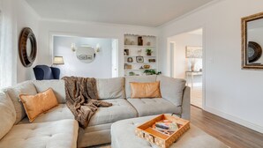 A living room with a sectional sofa, a coffee table with magazines, and a wall-mounted shelf with decorative items. - Cozy Mtn-View Retreat w/ Yard: Near Hiking & Golf! (Ferron)