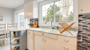 A kitchen with a white countertop, a double sink, and a window with a view of trees. - Cozy Mtn-View Retreat w/ Yard: Near Hiking & Golf! (Ferron)