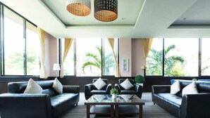 Una habitación de hotel moderna con un ventanal grande, un sofá de cuero negro, una mesa de centro de vidrio y una alfombra a rayas.