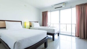 Una habitación de hotel con dos camas, un ventanal con cortinas y un equipo de aire acondicionado.