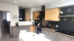 A modern kitchen with a white dining table, grey cabinets, and a black backsplash. - Welcome to our Mouscron Cocoon (Mouscron)