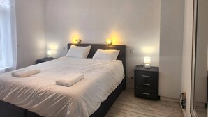 A neatly made bed with white linens and two pillows, flanked by bedside tables with lamps. - Welcome to our Mouscron Cocoon (Mouscron)